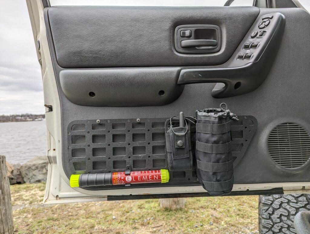 Trail & Co. Jeep XJ Front Door MOLLE Panel installed and holding a fire extinguisher, walkie talkie and cup-holder pouch.